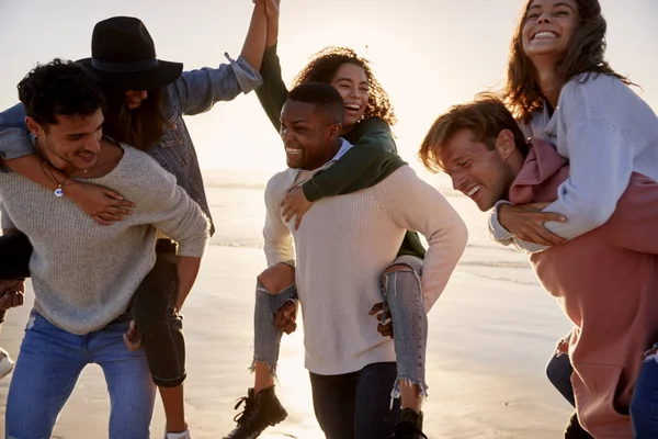 Grupp Vänner Med Piggyback Race Vintern Beach Tillsammans — Stockfoto