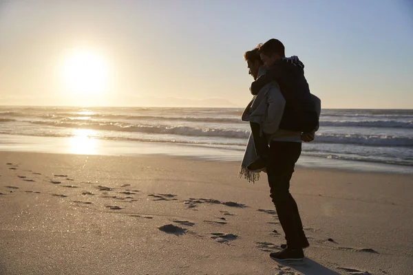 父亲的剪影在冬天海滩送儿子背驮 — 图库照片