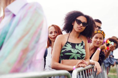 Group Of Young Friends Waiting Behind Barrier At Entrance To Music Festival Site clipart