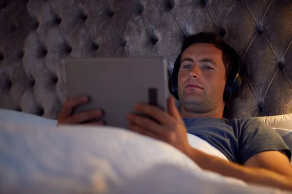 Чоловік Носить Бездротові Навушники Лежачи Ліжку Дивитися Цифровий Планшет Перед — стокове фото
