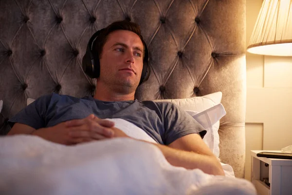 头戴无线耳机的男人睡觉前听音乐或播客 — 图库照片