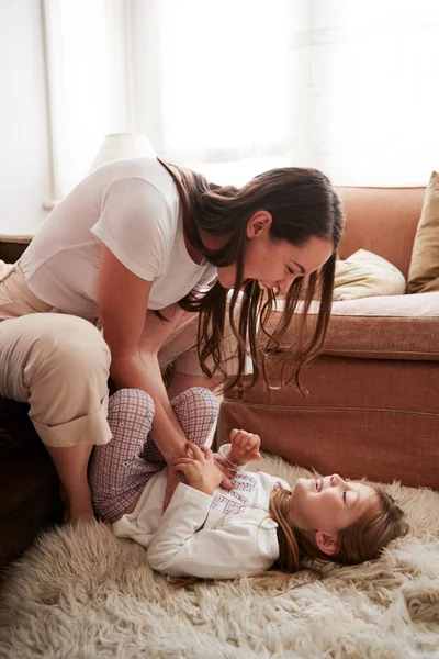 Mutter Kitzelt Tochter Als Sie Auf Teppich Wohnzimmer Liegt — Stockfoto