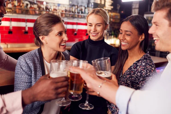 仕事の後にバーで酒と社交のために会うと同時にトーストを作る男性と女性の友人 — ストック写真