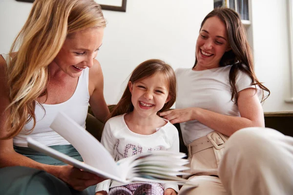 Gleichgeschlechtliches Paar Liest Buch Mit Tochter Hause Während Sie Kitzelt — Stockfoto