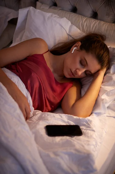 Vrouw Slapen Bed Het Dragen Van Draadloze Oortelefoons Aangesloten Mobiele — Stockfoto