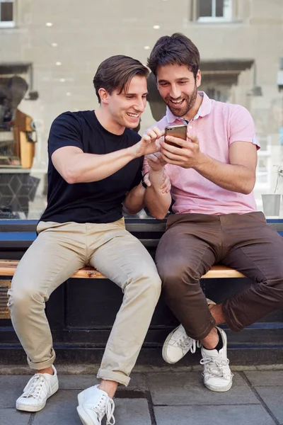 Hombre gay pareja sentado fuera café tienda buscando en social me —  Fotos de Stock