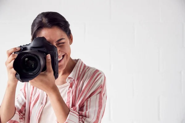 Vrouwelijke fotografe met camera op foto schieten tegen witte Stu — Stockfoto