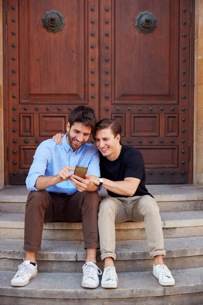 Мужчина гей пара в отпуске сидя на улице на ступенях постройки — стоковое фото