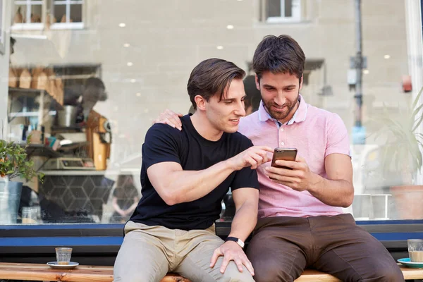 Hombre gay pareja sentado fuera café tienda buscando en social me — Foto de Stock