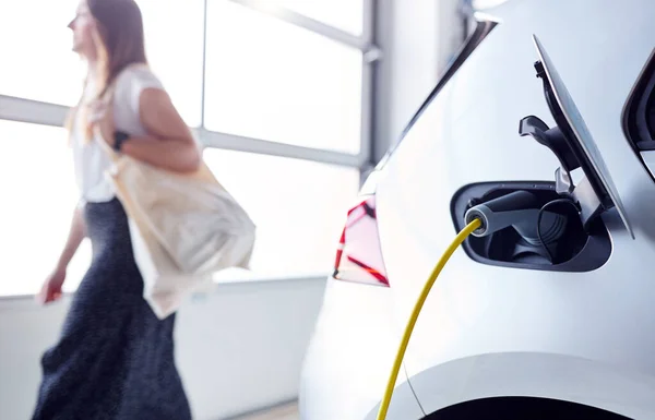 Женщина Ходит Магазинам Оставляя Электрический Автомобиль Зарядить Парковке — стоковое фото