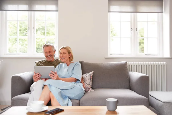 Casal Sênior Sentado Sofá Salão Casa Usando Tablet Digital Juntos — Fotografia de Stock