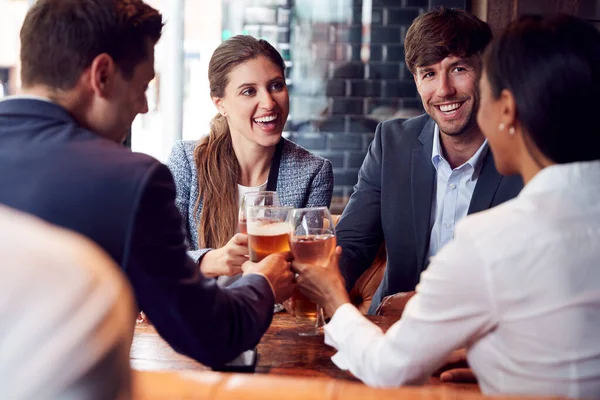 飲み物のために出会い 仕事の後でバーで社交的なトーストを作るビジネス同僚のグループ — ストック写真