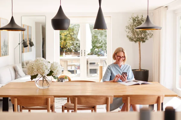 Senior Woman Avslappnande Med Tidningen Hemma Tittar Mobiltelefon Sitter Vid — Stockfoto