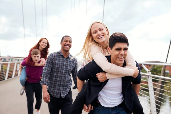 Studentinnen Mit Männern Die Frauen Huckepack Über Die Stadtbrücke Fahren — Stockfoto