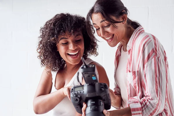 Sonriente fotógrafa sosteniendo la cámara con modelo en el estudio — Foto de Stock