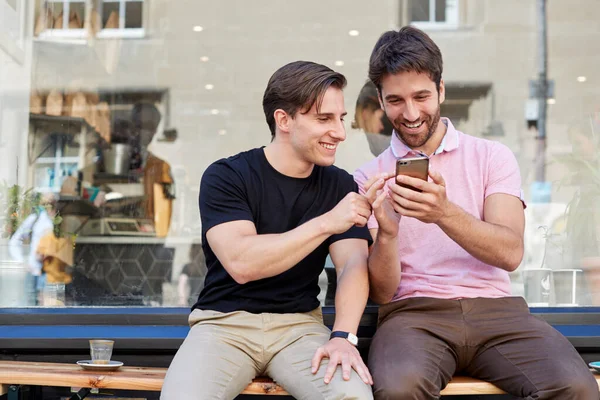 Hombre gay pareja sentado fuera café tienda buscando en social me —  Fotos de Stock