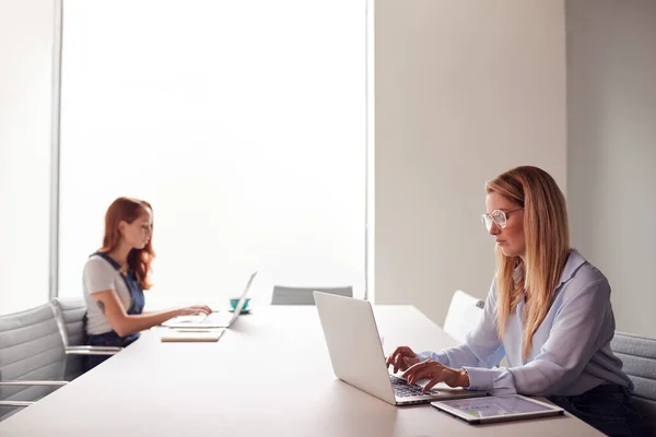 在现代会议室里 两名穿着休闲的年轻女商人在笔记本电脑上工作 — 图库照片