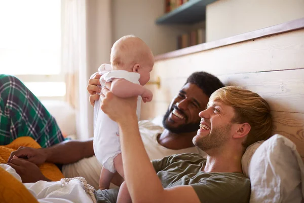 Loving Male Same Sex Couple Cuddling Baby Daughter Bedroom Home — Stock Photo, Image