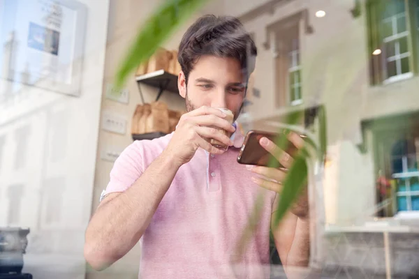 Kahve Dükkanındaki Genç Adam Camdan Dışarı Bakan Cep Telefonuna Bakıyor — Stok fotoğraf