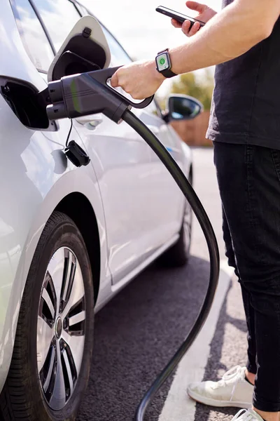 Hombre Cargando Vehículo Eléctrico Con Cable Mirando Aplicación Teléfono Móvil — Foto de Stock