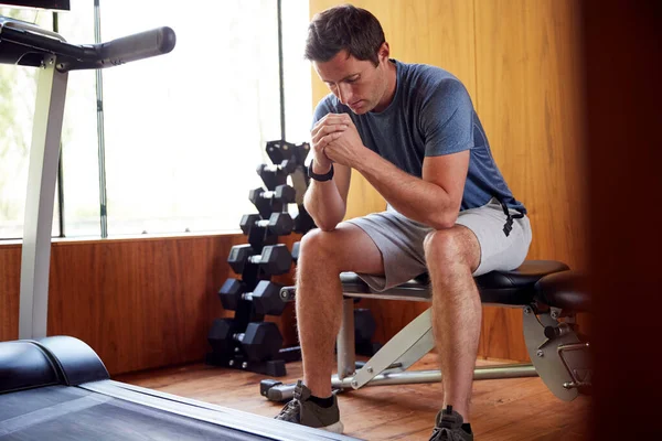 男子对家庭健身室体形坐在体重椅上的焦虑 — 图库照片