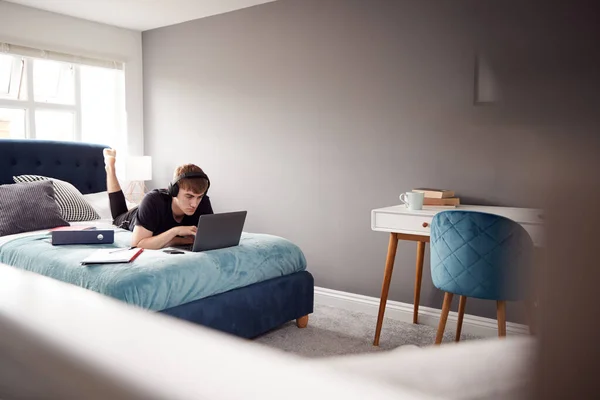 Estudiante Universitario Masculino Con Auriculares Acostado Cama Casa Compartida Trabajando — Foto de Stock