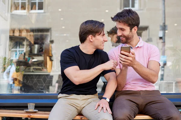 Hombre gay pareja sentado fuera café tienda buscando en social me —  Fotos de Stock