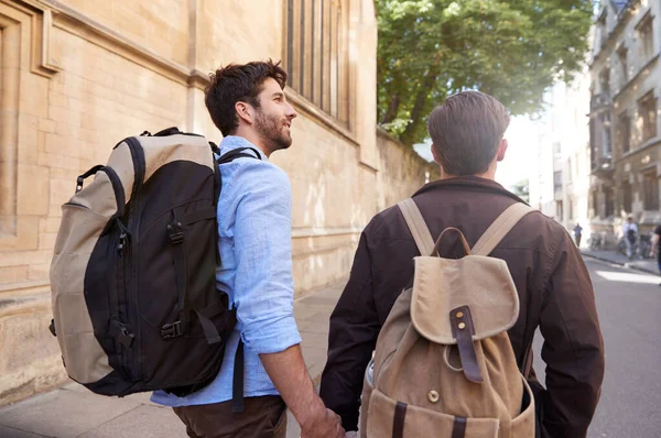 Bakifrån av manliga homosexuella par på semester bär ryggsäckar Holdi — Stockfoto