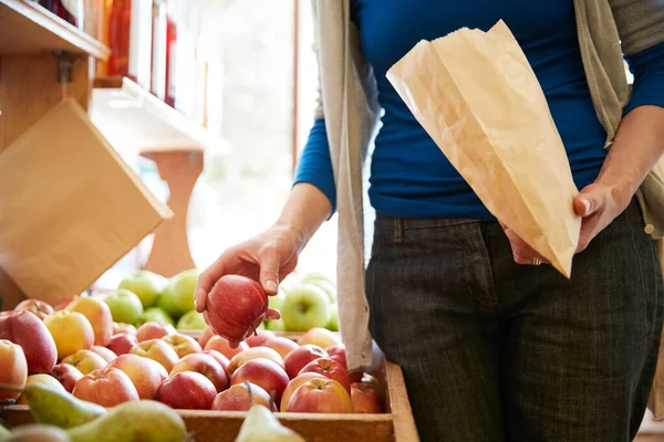 用纸袋在有机农场商店购买新鲜苹果来接近女性顾客 — 图库照片