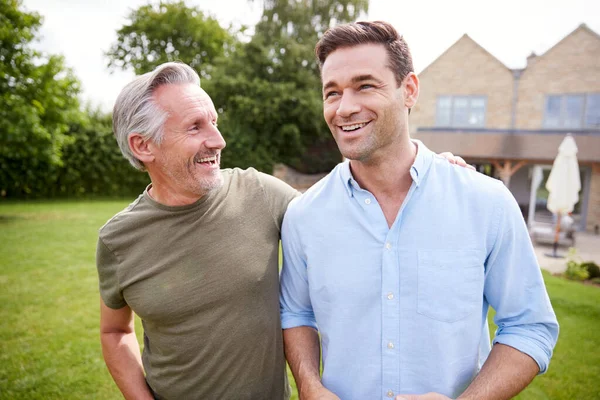 年长的父亲和成年的儿子一起在花园里散步和说话 — 图库照片