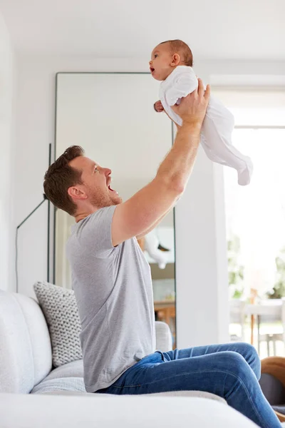 自宅のラウンジで空気中の3ヶ月の赤ちゃんの娘を持ち上げる愛するお父さん — ストック写真