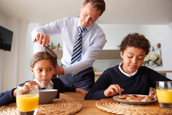 Businessman Father In Kitchen Brushing Hair And Helping Children With Breakfast Before School