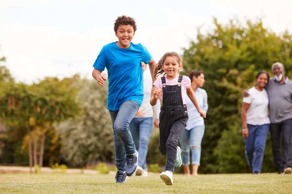 多世代混合レースとして前に走っている子供たち自宅で庭を歩く家族 — ストック写真