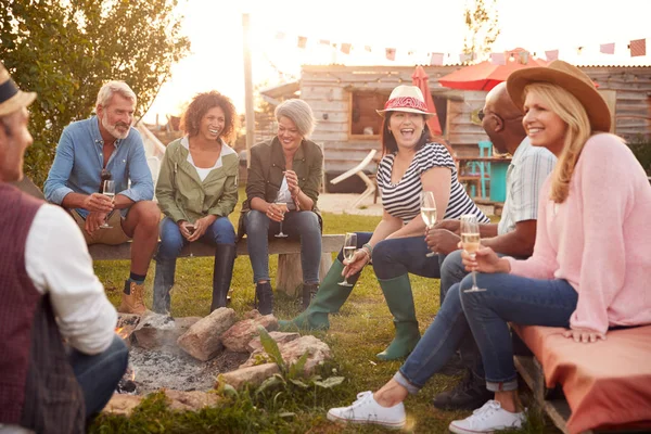 Grupa Dojrzałych Przyjaciół Siedzi Wokół Ognia Picie Outdoor Campsite Bar — Zdjęcie stockowe