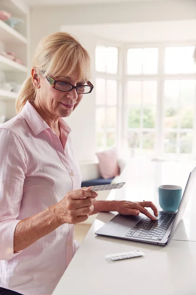 Mature Woman Home Looking Information Medication Online Using Laptop — ストック写真