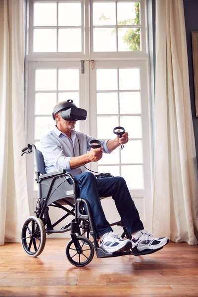 家中轮椅上的成熟残疾人头戴虚拟现实耳机 手持游戏控制器 — 图库照片