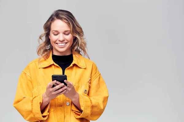 Studio Shot Smiling Mujer Joven Vestida Causalmente Usando Teléfono Móvil —  Fotos de Stock