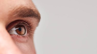 Extreme Close Up Of Eye Of Man Against White Studio Background clipart