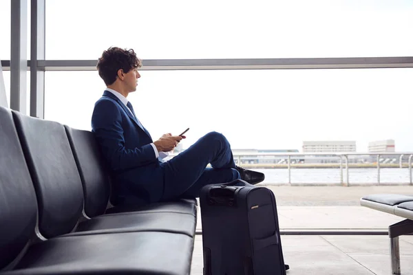 Empresario Sentado Salón Salida Del Aeropuerto Con Teléfono Móvil — Foto de Stock