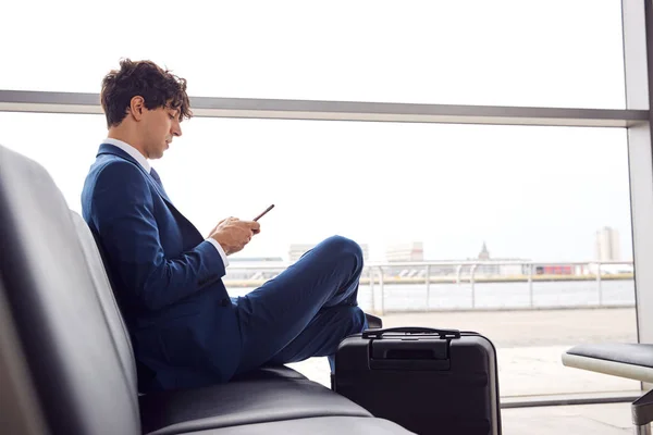 ビジネスマンが携帯電話を使って空港出発ラウンジに座る — ストック写真