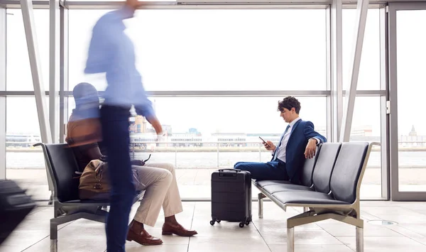 Geschäftsmann Sitzt Mit Handy Belebter Flughafen Abflughalle — Stockfoto