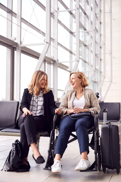 Geschäftsfrau Sitzt Flughafen Abflug Mit Kollegin Rollstuhl Und Redet Miteinander — Stockfoto