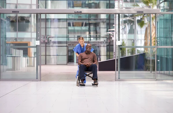 Krankenschwester Schrubbt Rollende Patientin Rollstuhl Durch Lobby Des Modernen Krankenhausgebäudes — Stockfoto