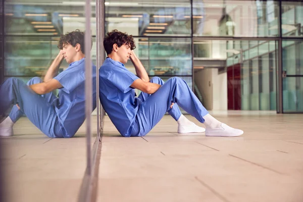 Unavený Mladý Mužský Lékař Nosí Drhnutí Sedí Proti Zdi Moderní — Stock fotografie