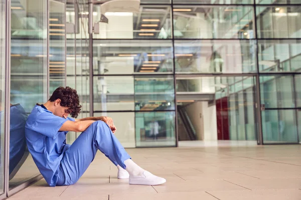 Zmęczony Młody Mężczyzna Lekarz Noszący Szorty Siedzi Ścianie Nowoczesnym Budynku — Zdjęcie stockowe
