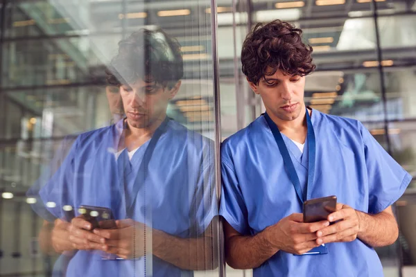 Joven Doctor Masculino Usando Exfoliantes Usando Teléfono Móvil Apoyado Contra — Foto de Stock