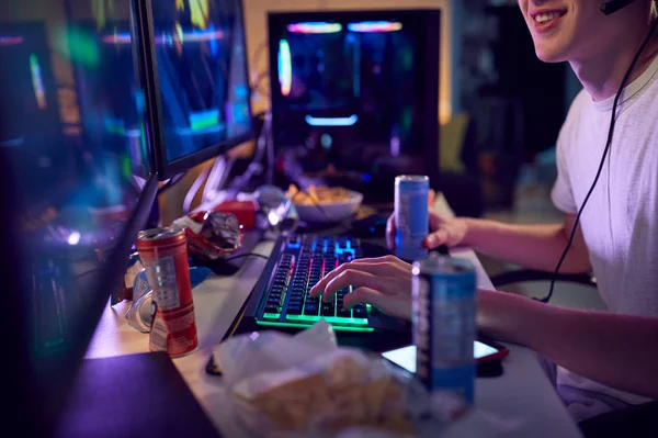十代の男の子は夜にデュアルコンピュータ画面を使用して自宅でカフェインエネルギードリンクゲームを飲む — ストック写真