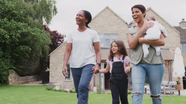 自宅で庭を歩いている3世代の家族からの娘と祖母と一緒に母赤ちゃんを保持 スローモーションで撮影 — ストック動画