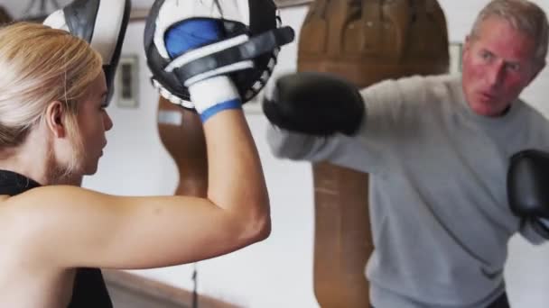 トレーニング手袋を使用してジムで若い女性コーチとシニア男性ボクサー スローモーションで撮影 — ストック動画