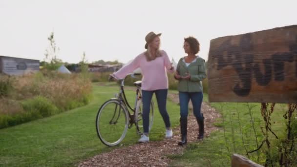 两个成熟的女性朋友骑着自行车在酸奶营地边走着 动作缓慢 — 图库视频影像